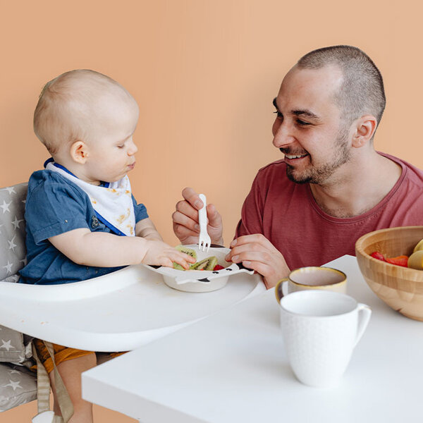 Mensch füttert lächelnd ein Baby