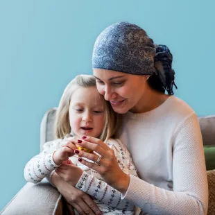 Mutter und Tochter sitzen auf der Couch und kuscheln zusammen