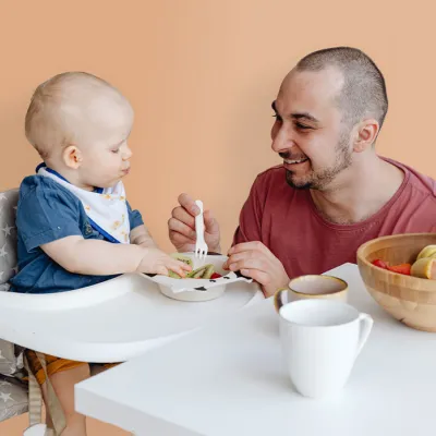 Mensch füttert lächelnd ein Baby