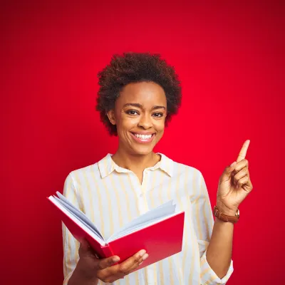 Junger Mensch mit Afro-Frisur zeigt mit dem Zeigefinger in die obere Ecke